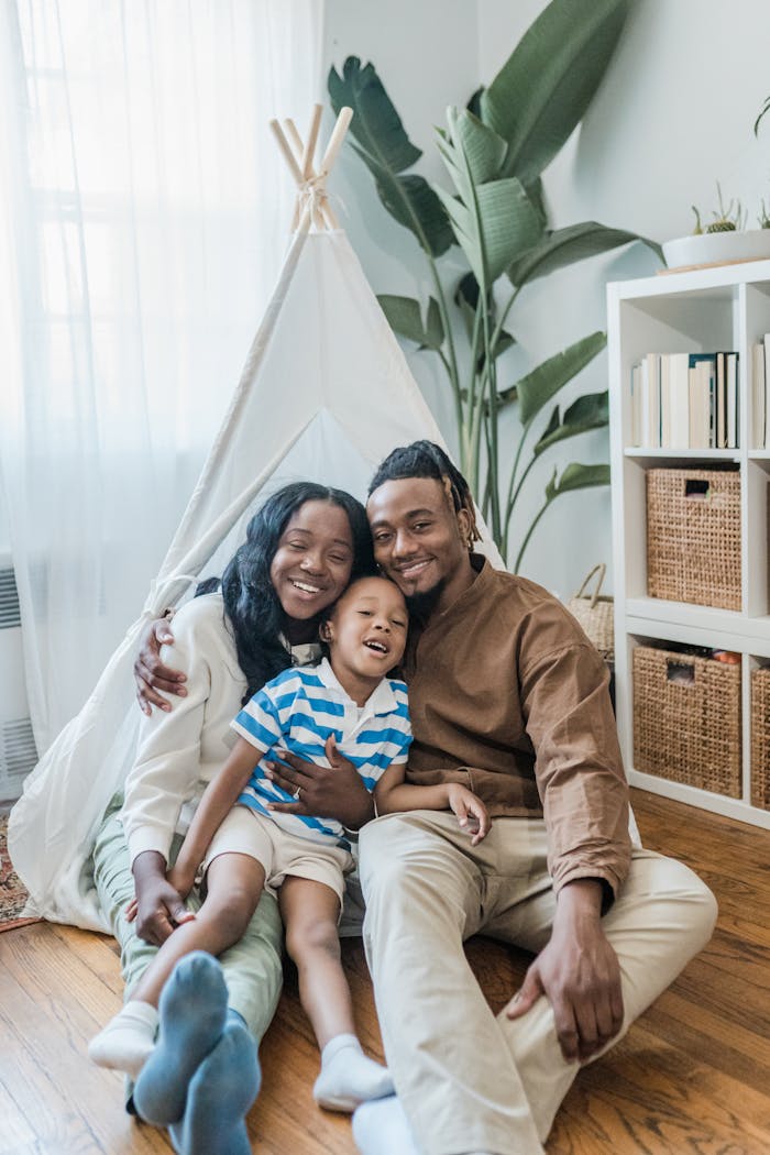A joyful family of three embracing in a cozy and bright living room.
