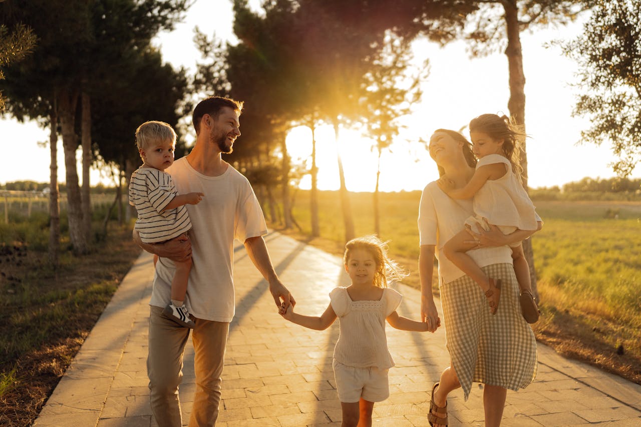 A joyful family walking together on a sunlit path during sunset, enjoying an outdoor stroll.